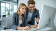 © Ada - Working together on project. Two young business colleagues working on computer. smiling young businesswoman with blonde hair typing on a computer keyboard in a bright, modern office setting.