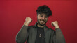 © Krakenimages.com - Young man with beard expressing happiness against red background, showcasing a cheerful and friendly demeanor, perfect for depicting positive emotions.