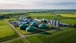 © Margarita Ratatosk - Aerial view of modern biogas plant in vast green rural field. Renewable energy production facility for sustainable power generation.