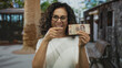 © Krakenimages.com - Woman smiling holds mexican pesos on urban street, showcasing currency outdoors with happy expression and cheerful demeanor, highlighting middle-aged hispanic female with money in hand.