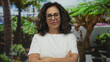 © Krakenimages.com - Hispanic middle aged woman in white t shirt crosses bare arms in green park outdoors under palm trees; denial rejection.