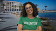 © Krakenimages.com - Middle age hispanic volunteer crosses arms and smiles on seaside promenade; volunteering service kindness.