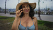 © Krakenimages.com - Woman smiling in bikini and hat standing on promenade near beach at seaside outdoors showcasing summer relaxation.