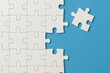 © mankong - White Puzzle Pieces on Blue Background with One Piece Missing and Right Next to the Puzzle Showing Completion and Creativity Concepts