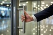 © Creativeraf - Businessman opening a modern glass door with a metal handle