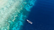 © AmazingAerialAgency - Aerial view of a white boat anchored on the turquoise waters near the shore of Menjangan Island, where snorkelers and divers explore the vibrant coral reefs, Menjangan Island, Bali, Indonesia.