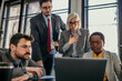 © La Famiglia - Business people having a serious meeting using laptop in the office