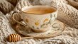 © Bimha - Cozy teacup with floral design on a knitted blanket. Steam rising from a warm beverage
