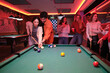 © Ladanifer - Group of young friends enjoying a game of pool in a billiard hall, socializing and having drinks