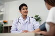 © Natee Meepian - Healthcare. Doctor smiling and engaging with patient during consultation.
