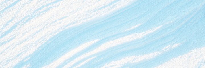 Wall Mural - Wide panoramic winter background with snowy ground. Natural snow texture. Wind sculpted patterns on snow surface.