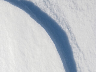 Wall Mural - Beautiful winter background with snowy ground. Natural snow texture. Wind sculpted patterns on snow surface. Closeup top view with copy space.