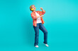 © deagreez - Elderly woman joyfully dancing with headphones on a vibrant turquoise background showcasing a fun and active lifestyle