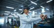 © Gorodenkoff - Multiethnic Female Engineer in a Mixed Reality Headset Standing in a High Tech Manufacturing Facility, Using Modern Technology to Operate Precision Engineering Tools at a Factory