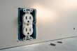 © michnik101 - Standard dual electrical outlet mounted in blue junction box inside drywall showing progress of interior electric work