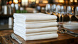 © Ketut Suki - A stack of white linen napkins on a wooden table in a restaurant setting.