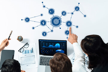 Poster - A modern office scene showcasing a collaborative team discussing business strategy and analytics with visual data charts and graphs displayed on a laptop. Amity