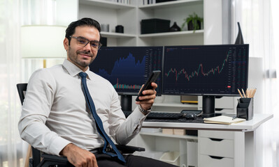 Poster - Profile of successful in smiling trader businessman looking at camera with holding phone two stock exchange investment screens in dynamic financial technology graph stock market at office. Surmise.