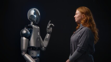 Fototapete - Futuristic Human-Machine Concept: Visualization of Young Woman Speaking with High-Tech Humanoid Robot. Symbol of Connection, Collaboration and Harmony Between Humanity and Artificial Intelligence.