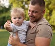 © New Africa - Smiling dad and his newborn baby outdoors. Happy Father's Day