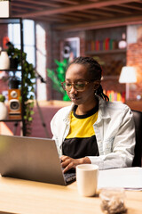 Poster - Student at home browsing internet on notebook, doing homework, researching information online. African american girl in apartment reading articles on laptop for school tasks