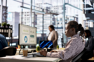 Poster - African american businesswoman managing administrative tasks at desk, reviewing organizational performance metrics for success. Skilled manager analyzing data focused on strategic planning.