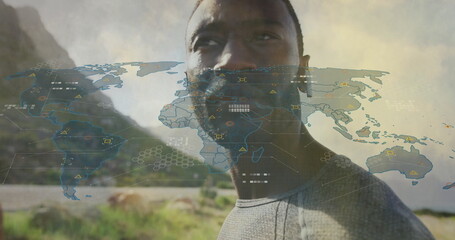 Poster - Standing man wearing shirt viewing map overlay on coastal hillside, with earbud and data nodes