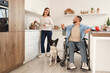 © Pixel-Shot - Young man in wheelchair, with wife and dog cooking in kitchen