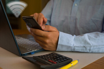 Businessman using smartphone and laptop in office. Man scrolls social media, checks email, manages business processes, works remotely. Modern tech makes easier do job. Effective time management.