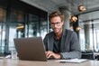 © ttonaorh - Mature professional man using laptop in modern office lounge, portraying remote work, business confidence, and digital productivity.