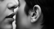 © Phaimanee - Black and white photograph depicting one person whispering into another person's ear. The focus is on the mouth of the speaker and the ear of the listener, conveying a sense of intimacy or secrecy.