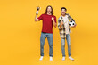 © ViDi Studio - Full body young winner two friends men sport fans wears casual clothes cheer up support football team hold soccer ball golden cup watch tv live stream isolated on yellow background. Leisure concept.