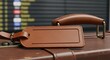 © ALLmost - Close-up of a brown leather luggage tag attached to a suitcase, with an airport departure board visible in the blurred background.