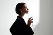 © EricMiguel - Elegant woman in black dress enjoying a glass of white wine with closed eyes in a minimalist setting