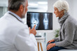 © Olha Havelia - A doctor in a white coat discussing a knee fracture with an elderly woman in a medical office, pointing to an X-ray on a monitor. The woman listens attentively while sitting on an