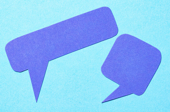 Blank cut out paper speech bubbles with copy space for text on blue background, flat lay top view conceptual conversation backdrop