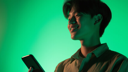 Asian male smiling suspiciously while using his smartphone, copy space
