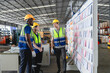 © AU USAnakul - Multiracial logistics team in automotive warehouse discussing workflow by planning board, showing collaboration and efficiency, Logistics briefing in warehouse