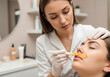 © PictoAi - A woman esthetician in a white coat applies a warm wax treatment to the upper lip of a client lying on a treatment bed.