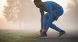 © Marpe - Man in blue athletic wear tying shoelaces on a foggy field preparing for a run or workout outside on transparent background