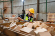 © AU USAnakul - Male staff member enjoying timber work, holding a square wooden piece inside production warehouse, contributing to pallet material preparation and sustainable reuse planning.
