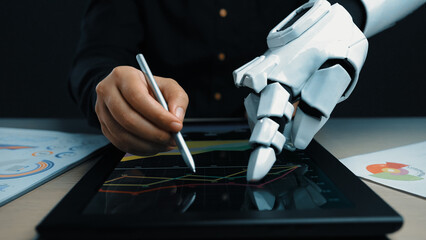 Poster - A human hand and a robotic hand cooperate in analyzing digital market data on a tablet, illustrating the synergy between technology and human insight in finance.Noogenesis