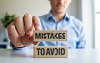 © Fahad - Business owner holding wooden blocks with 'Mistakes to Avoid' message