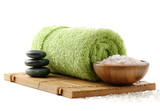 Rolled light green towel, spa stones, and bowl of bath salt on a bamboo mat
