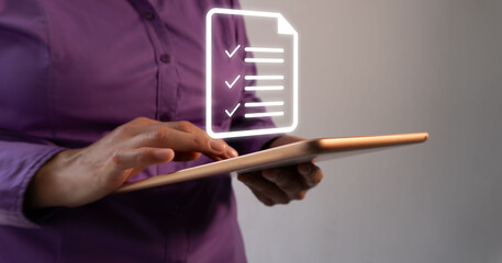 Poster - Business person working on a tablet with a floating virtual icon of a document with several checkmarks