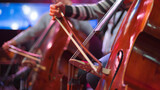 girl playing cello in orchestra on stage