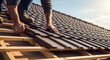 © justsann - Close-up of a skilled worker's hands placing new brown tiles on a house roof under a clear sky, an essential part of a professional roof repair project.
