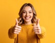 © Somad - Cheerful young woman with blonde hair giving thumbs up gesture on yellow background