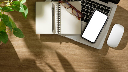 Wall Mural - Top view of a laptop, smartphone with blank screen, notebook, and pen on a wooden desk.