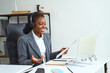 © puhhha - Woman in a Business Suit Conducting an Online Meeting or Presentation With a Headset, Expressing Positivity and Confidence in a Well-Lit Modern Office Environment, Representing Technology